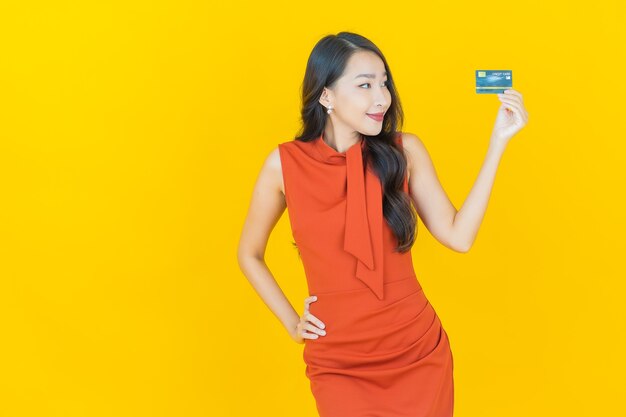 Portret mooie jonge Aziatische vrouw glimlach met creditcard op geel