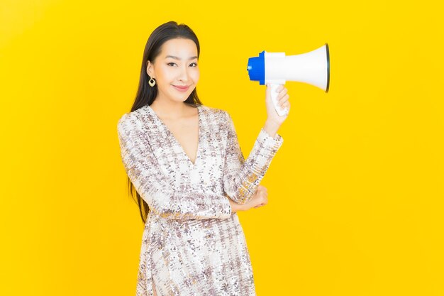 Portret mooie jonge Aziatische vrouw glimlach met megafoon op geel mega