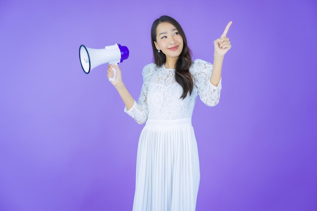 Portret mooie jonge Aziatische vrouw glimlach met megafoon op kleur achtergrond