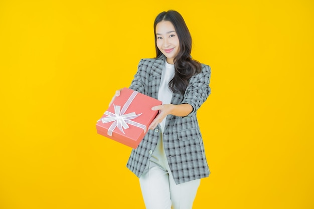 Portret mooie jonge Aziatische vrouw glimlach met rode geschenkdoos op kleur achtergrond