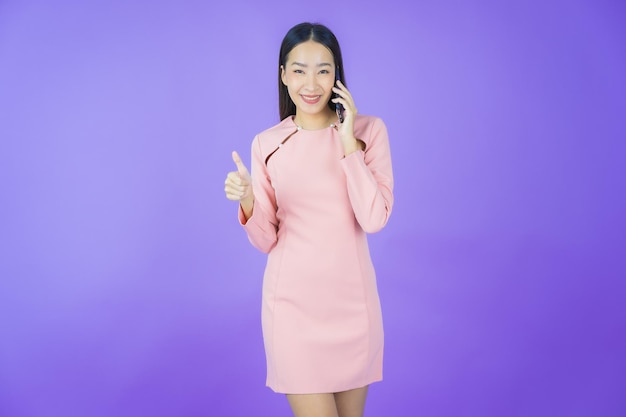 Portret mooie jonge aziatische vrouw glimlach met slimme mobiele telefoon op kleur achtergrond