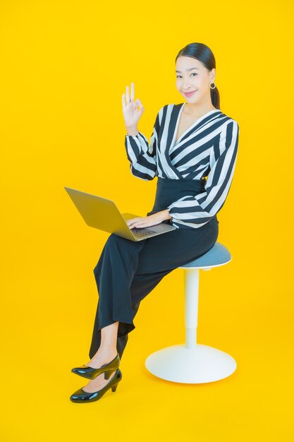 Portret mooie jonge Aziatische vrouw glimlach op geel