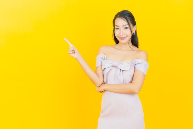 Portret mooie jonge Aziatische vrouw glimlachend en poseren op kleur muur