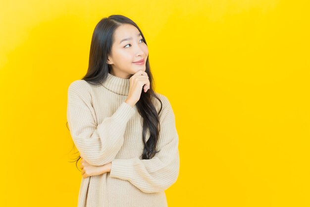 Portret mooie jonge Aziatische vrouw glimlacht met actie op gele muur yellow