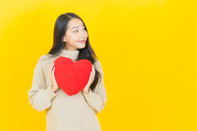 Portret mooie jonge aziatische vrouw glimlacht met hart kussen vorm op gele muur on