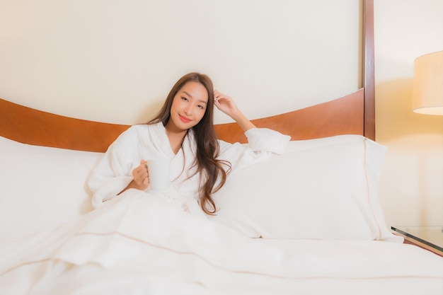 Portret mooie jonge Aziatische vrouw glimlacht ontspannen op bed in slaapkamer interieur