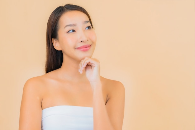 Portret mooie jonge Aziatische vrouw in spa met natuurlijke make-up op beige