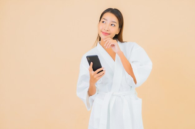 Portret mooie jonge Aziatische vrouw met behulp van slimme mobiele telefoon op beige