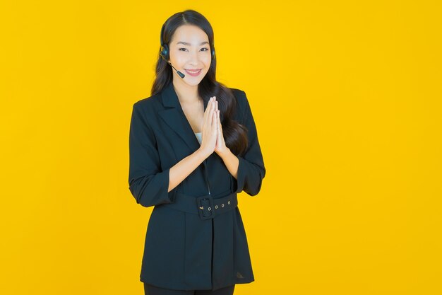Portret mooie jonge aziatische vrouw met callcenter klantenservice op geel geel