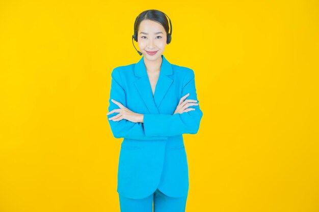 Portret mooie jonge aziatische vrouw met callcenter klantenservice op geel