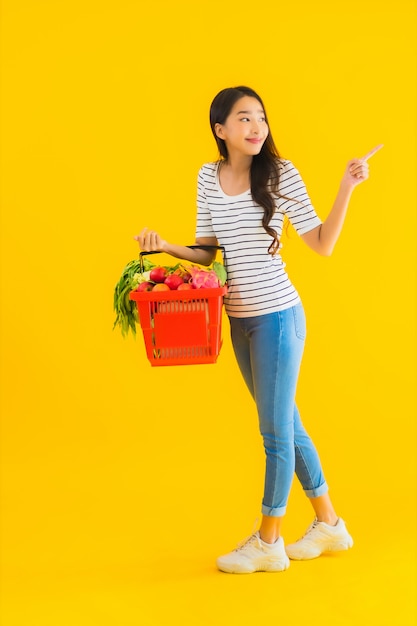 Portret mooie jonge Aziatische vrouw met de mand van de kruidenierswinkelmand van supermarkt in winkelcomplex