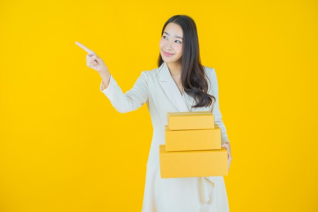 Portret mooie jonge Aziatische vrouw met doos klaar voor verzending op kleur achtergrond