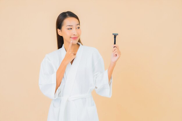 Portret mooie jonge Aziatische vrouw met het scheren op beige