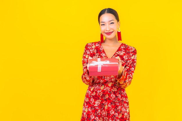 Portret mooie jonge Aziatische vrouw met rode geschenkdoos op kleur muur