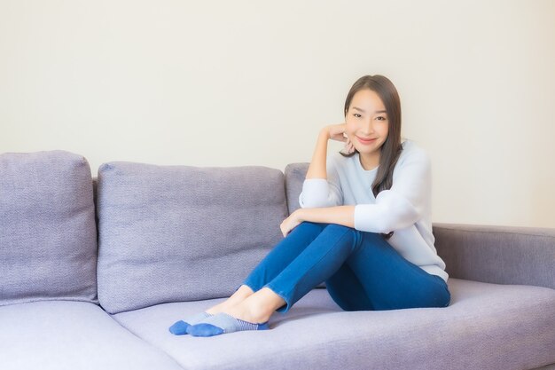 Portret mooie jonge aziatische vrouw ontspannen glimlach op de bank in de woonkamer