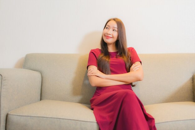 Portret mooie jonge Aziatische vrouw ontspannen op de bank in woonkamer interieur