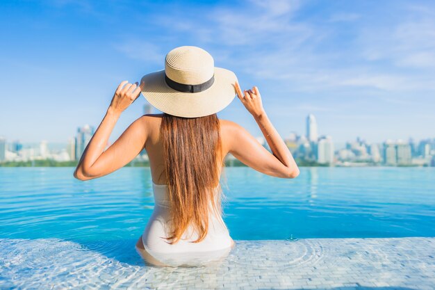 Portret mooie jonge Aziatische vrouw ontspannen rond buitenzwembad met uitzicht op de stad
