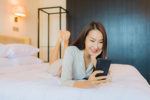 Portret mooie jonge aziatische vrouw op bed met slimme mobiele telefoon