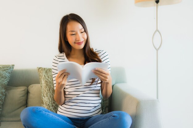 Portret mooie jonge Aziatische vrouwen die boek met koffiekop lezen