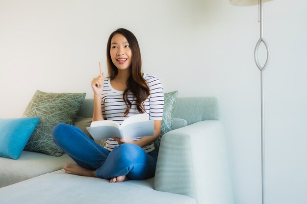 Portret mooie jonge Aziatische vrouwen die boek met koffiekop lezen