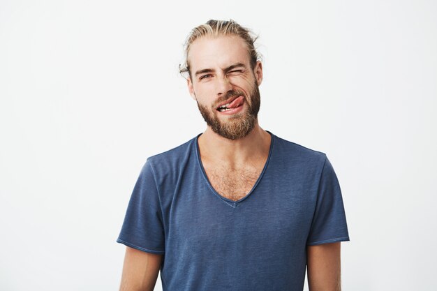 Portret og mooie jonge man met stijlvolle haren en baard maken grappig en dom gezicht