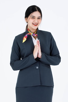 Portret studio shot van aziatische professionele mooie beleefde vrouwelijke vliegtuig stewardess in formeel uniform staande glimlachende blik op camera hand in hand betalen respect groet op witte achtergrond.