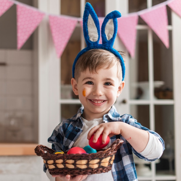 Portret van aanbiddelijke kleine jongen die een mand met eieren houdt