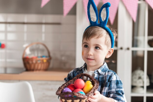 Portret van aanbiddelijke kleine jongen die een mand met eieren houdt