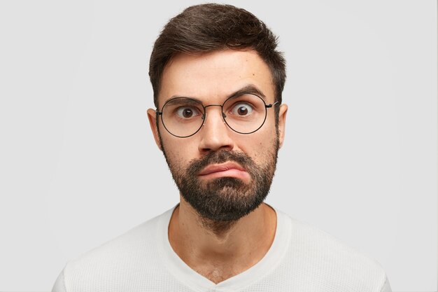 Portret van aantrekkelijke jonge man met donkere stoppels close-up, ziet er verrassend uit
