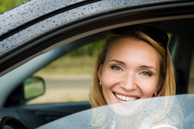 Portret van aantrekkelijke jonge vrolijke vrouw in de nieuwe auto - buitenshuis