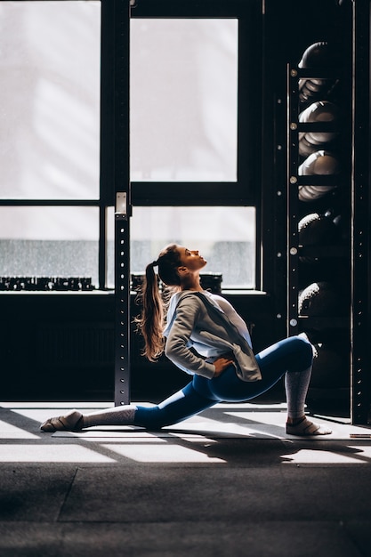 Gratis foto portret van aantrekkelijke jonge vrouw die yoga of pilates oefening doet