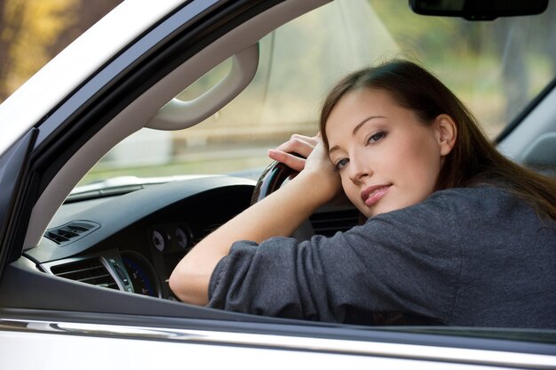 Portret van aantrekkelijke jonge vrouw in de nieuwe auto - buitenshuis