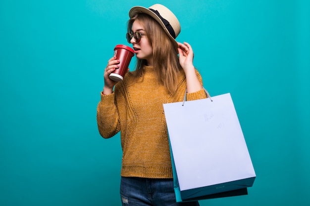 Portret van aantrekkelijke jonge vrouw met boodschappentassen en papieren kopje verse koffie