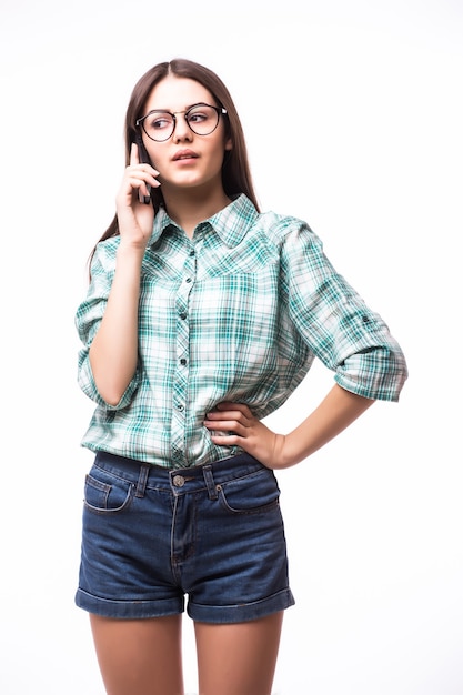 Portret van aantrekkelijke Spaanse vrouw op blauw t-shirt die op haar cel spreekt terwijl status en op studio glimlacht