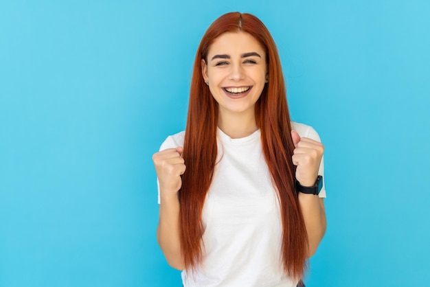 Portret van aantrekkelijke vrolijke gelukkige vrouw die zich verheugt over succes geïsoleerd op levendig blauw