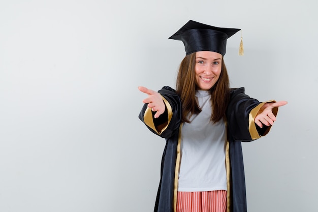 Portret van afgestudeerde vrouw armen openen voor knuffel in vrijetijdskleding, uniform en op zoek vrolijk vooraanzicht