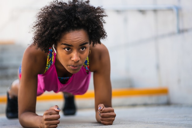 Portret van afro-atletenvrouw die planken op de vloer buitenshuis doet