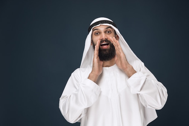 Portret van Arabische Saoedische zakenman op donkerblauwe studiomuur