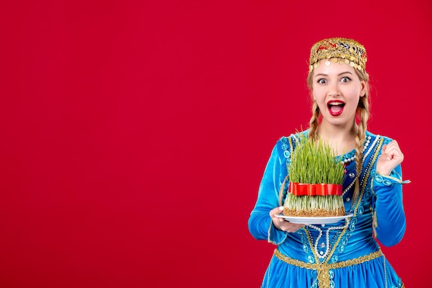 Portret van azeri vrouw in traditionele kleding met groene semeni op rode achtergrond concept danser lente etnische