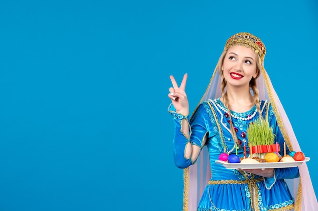 Portret van azeri-vrouw in traditionele kleding met novruz xonca blauwe achtergrond spring etnische gelddanser