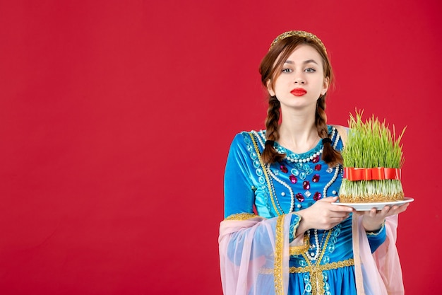 Gratis foto portret van azeri vrouw in traditionele kleding met semeni op rood