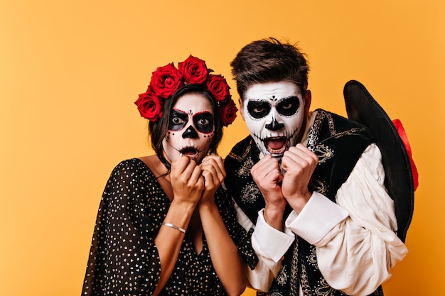 Portret van bange man en vrouw met bloemen in haar haar. Geschokte jongeren met gezichtskunst