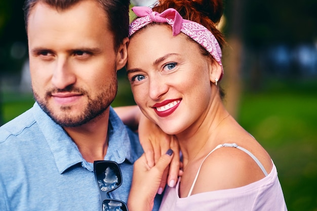 Portret van bebaarde man en roodharige vrouw in een stadspark.