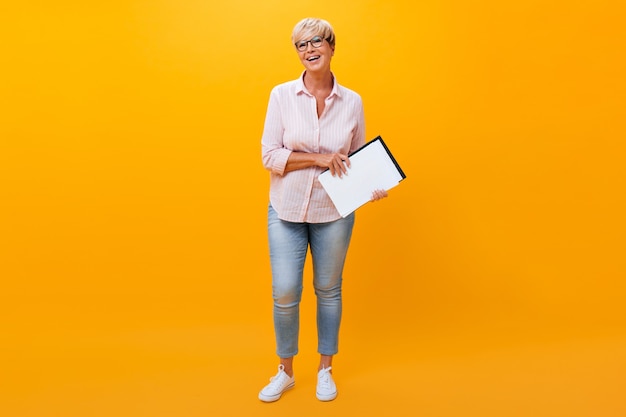 Portret van bedrijfsdame in jeans en overhemd op oranje achtergrond
