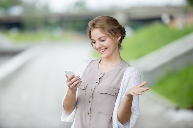 Portret van blije vrouw die op het smartphone scherm kijkt