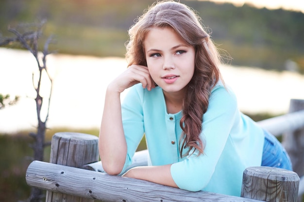 Gratis foto portret van blond schattig tienermeisje in een blauwe jurk over natuurlijke buitenveld.