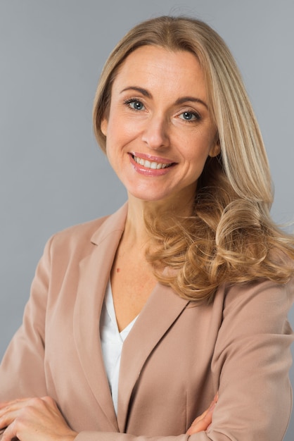 Portret van blonde zekere jonge onderneemster tegen grijze achtergrond