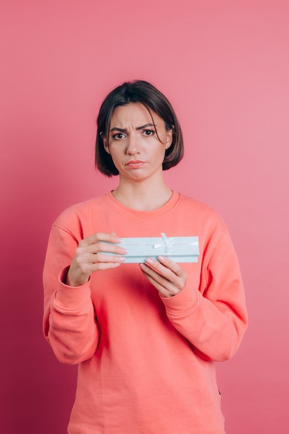 Portret van boos gefrustreerd meisje openen geschenkdoos geïsoleerd op roze achtergrond