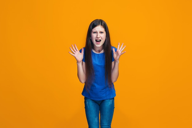 Portret van boos tienermeisje op een oranje studio