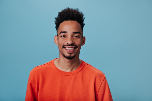 Portret van Brunett-man kijkt in de camera op blauwe muur